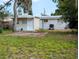 Back of home featuring large backyard, grass, concrete slab, and external AC unit at 1906 E 98Th Ave, Tampa, FL 33612
