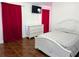 Bright bedroom featuring tile floors, red curtains, white dresser, and TV mounted above it at 1906 E 98Th Ave, Tampa, FL 33612