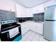 Modern kitchen with white cabinets, stainless steel appliances, and tile backsplash at 1906 E 98Th Ave, Tampa, FL 33612
