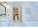 Bathroom featuring a dual vanity, standing shower, soaking tub, and a rustic accent wall at 1931 Jaudon Rd, Dover, FL 33527