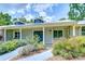 Charming home entrance featuring a blue door, dormer windows, and lush landscaping at 1931 Jaudon Rd, Dover, FL 33527