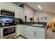 Open kitchen with stainless steel appliances, white cabinetry and a grey countertop peninsula at 2721 Baird Ct, Palm Harbor, FL 34684