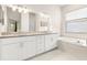 Primary bathroom featuring double sinks, granite countertops, and a soaking tub at 3023 Minuteman Ln, Brandon, FL 33511
