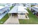 Aerial view of a cozy home featuring a covered parking spot, patterned driveway and green surroundings at 37105 Lois Ave, Zephyrhills, FL 33542