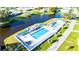 Aerial view of two community pools near a pond with lounge chairs and green grass at 37105 Lois Ave, Zephyrhills, FL 33542
