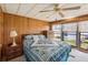 Cozy bedroom with wood paneling, large bed, and natural light from the window at 37105 Lois Ave, Zephyrhills, FL 33542