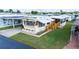 Bright mobile home with landscaped lawn, featuring a covered porch and accessible ramp at 37105 Lois Ave, Zephyrhills, FL 33542