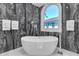 Modern bathroom features a luxurious soaking tub with marble accent wall and bright window view at 5212 62Nd S Ave, St Petersburg, FL 33715