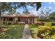 Inviting home featuring lush landscaping, a walkway, and a cozy porch with rocking chairs at 7535 Greystone Dr, Hudson, FL 34667