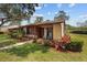 Charming single-story home featuring a well-maintained lawn, mature landscaping and inviting front porch with rocking chairs at 7535 Greystone Dr, Hudson, FL 34667