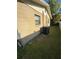 A view of the side of a one-story house with a small window, an A/C unit, and grass at 7620 32Nd S Ave, Tampa, FL 33619