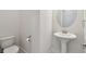 Bathroom featuring toilet, pedestal sink, and a round mirror at 8421 Ivy Stark Blvd, Wesley Chapel, FL 33545