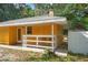 Side view of a yellow home with a white railing porch, chairs and mature trees at 8828 Jasmine Blvd, Port Richey, FL 34668