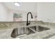Close up of stainless steel kitchen sink with black faucet and granite countertops at 9473 N Forest Hills Pl, Tampa, FL 33612