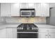 Bright kitchen featuring white cabinetry, stainless steel microwave and oven with a mosaic tile backsplash at 101 Marina Del Rey Ct, Clearwater, FL 33767