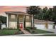 Charming two-story home featuring a red door, lush landscaping, and a three-car garage at 11029 Lynn Lake Cir, Tampa, FL 33625