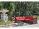 Outdoor seating area with a red sofa around a firepit and a statue surrounded by lush greenery for a serene atmosphere at 11029 Lynn Lake Cir, Tampa, FL 33625