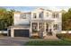 Two story home features a black 2-car garage door, gray brick, white siding, columns, and beautiful landscaping at 1172 Seville Ne Ln, St Petersburg, FL 33704