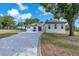 Modern home with a long paver driveway, manicured lawn, and mature landscaping, bathed in sunlight at 11921 Fort King Hwy, Thonotosassa, FL 33592