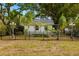Quaint cottage-style home with a black fence, lush landscaping, and mature trees at 1216 E Lambright St, Tampa, FL 33604