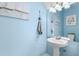Charming bathroom with pedestal sink, framed mirror, nautical decor, and soothing blue walls at 1271 Drew St, Clearwater, FL 33755