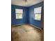 A bare bedroom with blue walls, stained carpet, and two windows at 12720 Jan St, San Antonio, FL 33576