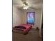 A small bedroom with a fan, window, a twin bed, and stained carpet at 12720 Jan St, San Antonio, FL 33576