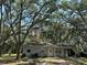 Charming single-story home featuring a quaint front porch and lush, mature trees surrounding the property at 12720 Jan St, San Antonio, FL 33576