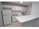 Efficient kitchen featuring white appliances, cabinets, and bar seating, illuminated by overhead lighting at 1400 Gandy N Blvd # 1705, St Petersburg, FL 33702