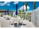 Outdoor seating area by the community lake and pool with white chairs and tables and blue umbrellas at 1400 Gandy N Blvd # 1705, St Petersburg, FL 33702