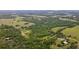 The aerial picture showcases dense woodlands, open grasslands, surrounding homes, and a pond at 14409 Curley Rd, Dade City, FL 33525