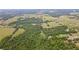 This aerial view displays the property's dense woodland, extensive grasslands, scattered homes, and nearby orchard at 14409 Curley Rd, Dade City, FL 33525