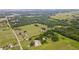 An aerial view featuring lush woodlands, extensive grasslands, nearby residences, and a distant pond at 14409 Curley Rd, Dade City, FL 33525