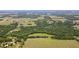 Aerial view showcasing the property's dense woodlands, open fields, surrounding residences, and nearby grove at 14409 Curley Rd, Dade City, FL 33525