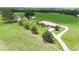 Aerial view of home with manicured lawn, mature trees, fenced perimeter, and paved driveway at 14409 Curley Rd, Dade City, FL 33525