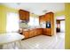 Classic kitchen featuring wood cabinetry, white tile floors, and vintage appliances with bright yellow walls at 14409 Curley Rd, Dade City, FL 33525