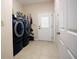 Bright laundry room featuring tile floor, modern washer and dryer, and convenient door to the outside at 14409 Curley Rd, Dade City, FL 33525