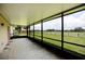 Screened in patio with a large outdoor space overlooking a grassy field and wooded trees at 14409 Curley Rd, Dade City, FL 33525