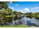 Beautiful community lake featuring stone structures, lush greenery, and serene water reflections under a partly cloudy sky at 14634 Mirasol Manor Ct, Tampa, FL 33626