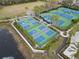 Aerial view of green and blue pickleball courts near a pond with palm trees on a sunny day at 14634 Mirasol Manor Ct, Tampa, FL 33626