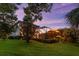 Twilight view of the backyard, showcasing the pool's ambiance and the home's outdoor living space at 1570 Marinella Dr, Palm Harbor, FL 34683