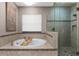Bright bathroom features soaking tub with faucet and bamboo tray, and a glass enclosed shower with mosaic tile flooring at 1570 Marinella Dr, Palm Harbor, FL 34683
