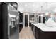 Modern kitchen with stainless steel refrigerator, dark cabinets, and a large island with a sink and pendant lights at 1570 Marinella Dr, Palm Harbor, FL 34683