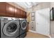 A modern laundry room with a front load washer and dryer, tile floors, cabinets, and a door at 1570 Marinella Dr, Palm Harbor, FL 34683