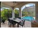 Covered patio featuring a dining area overlooking the screened-in pool and lush landscaping at 1570 Marinella Dr, Palm Harbor, FL 34683