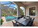 Covered patio with travertine floors featuring a dining area with views of the screened-in pool at 1570 Marinella Dr, Palm Harbor, FL 34683
