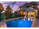 Screened pool with elegant lighting, lounge chairs, and home's exterior in the background at 1570 Marinella Dr, Palm Harbor, FL 34683