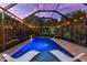 A tranquil screened pool area is enhanced by ambient string lights and comfortable chaise lounges at 1570 Marinella Dr, Palm Harbor, FL 34683