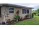 Tan, single-story home exterior featuring white-trimmed windows, plants, garden bed, and well-kept lawn at 1735 Cleveland St, Clearwater, FL 33755