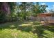 Spacious backyard featuring green grass, wood fence, and lush trees at 2903 Manor Ridge Pl, Valrico, FL 33596